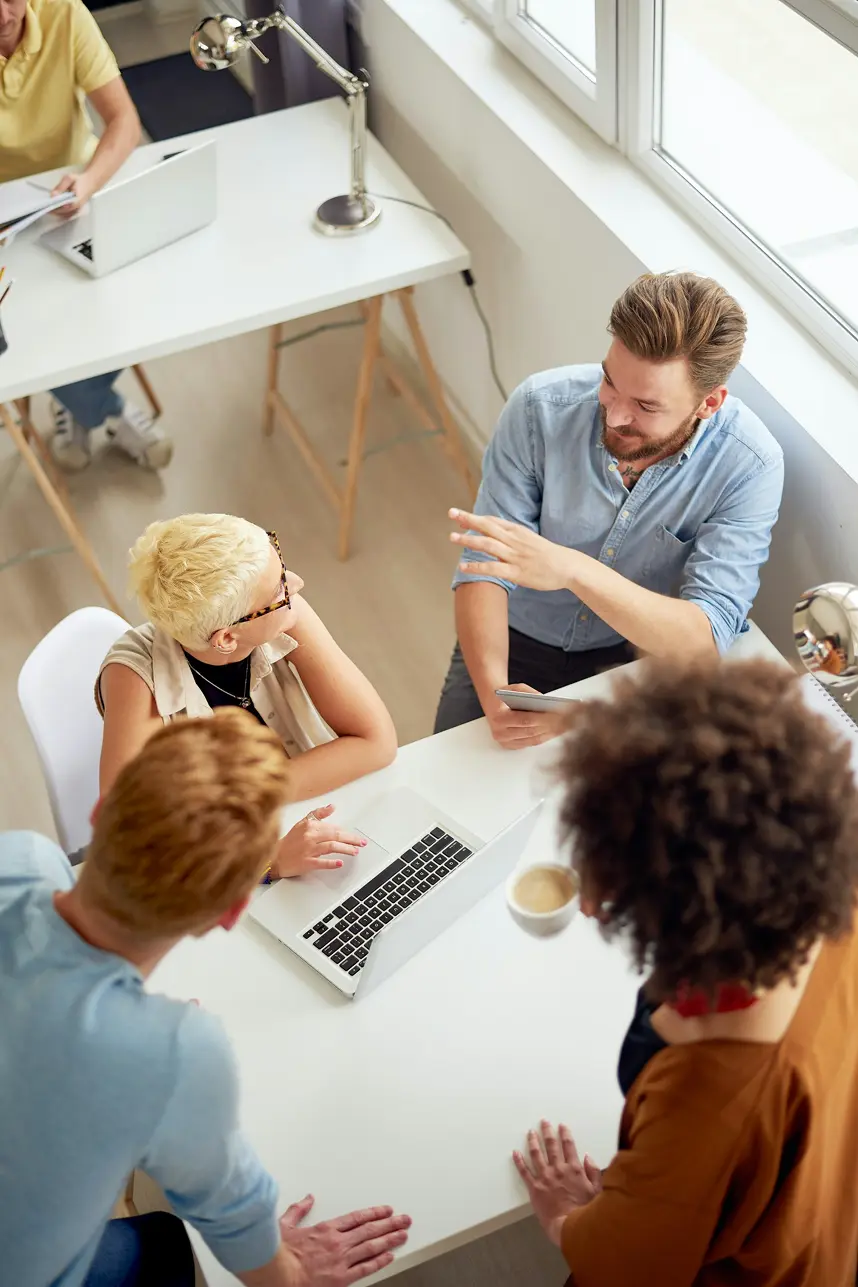 Team collaborating around a laptop discussing AI implementation
