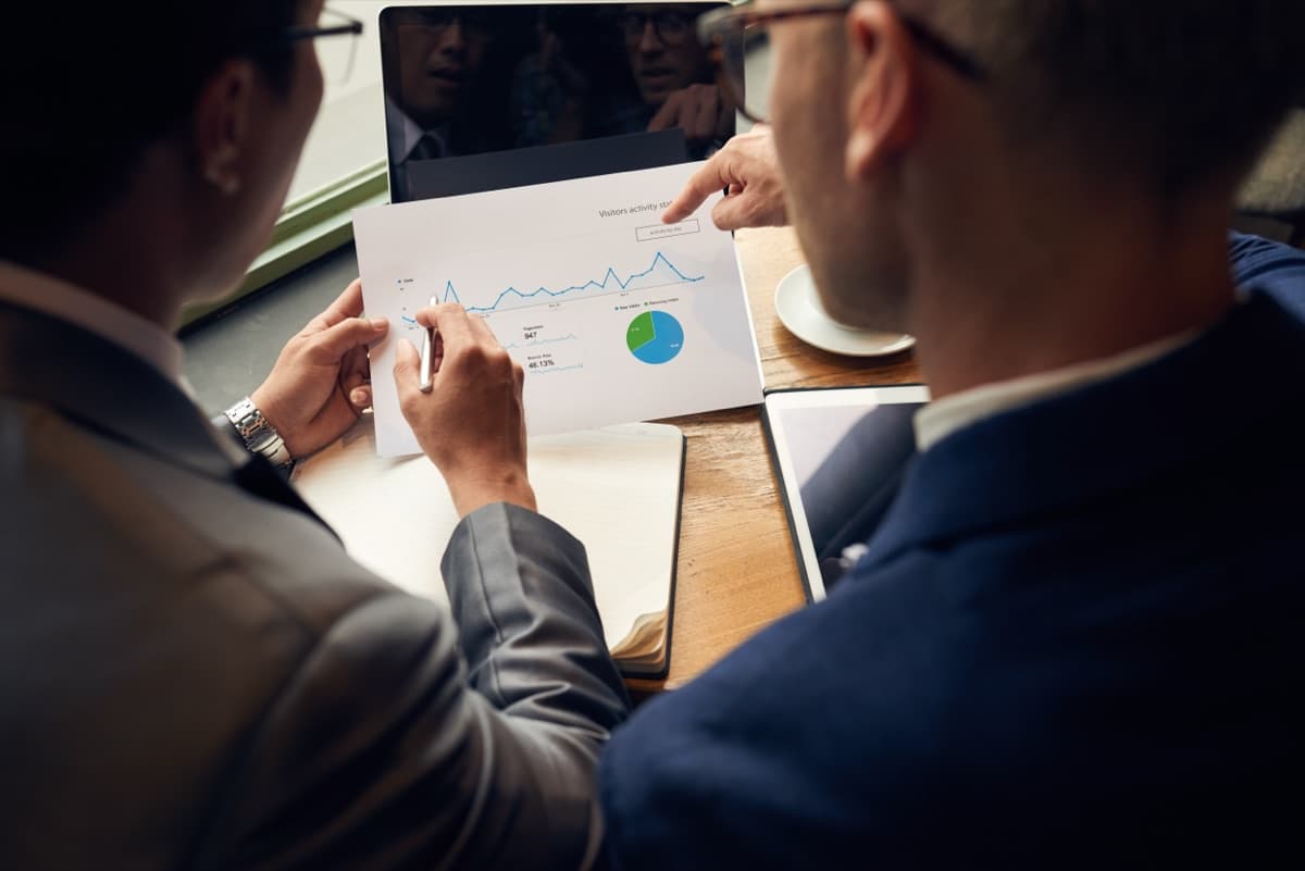 Two professionals analyzing a business performance chart, representing Sphere's predictive data-modeling approach behind PaveIQ