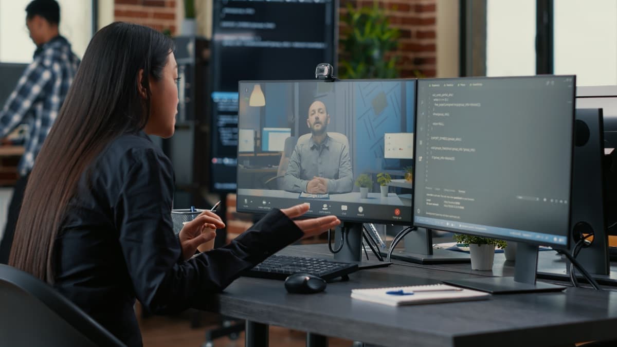 Team member on a video call with a remote colleague, discussing a coding deadline — coordinated delivery, not a headshot grid or resume stack