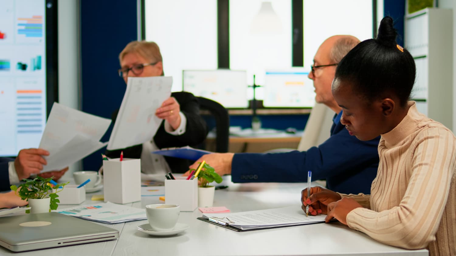 Membership and content team reviewing pilot documents and reports in a conference room