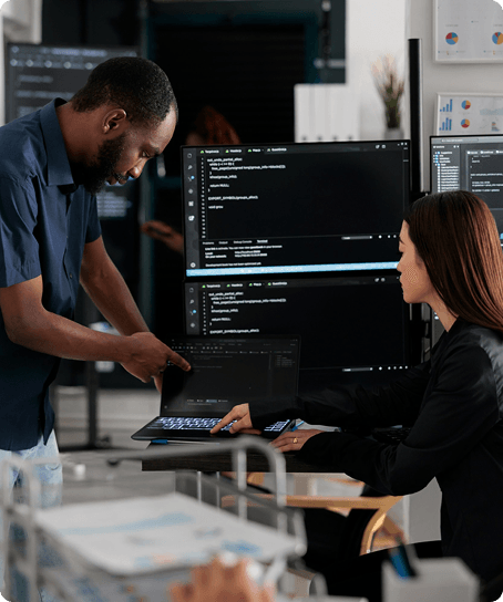 Engineers reviewing code on multiple monitors